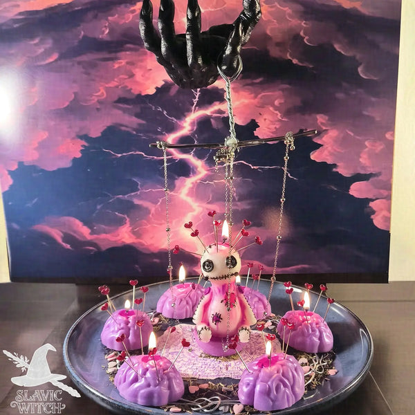 Pink voodoo doll candle with pins surrounded by lit pink candles on a plate, used in the Mental Marionette forced headwork spell ritual by Slavic Witch