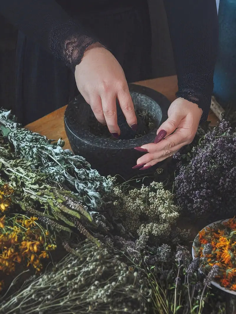 hands preparing herbs in mortar for personalised spellwork ritual